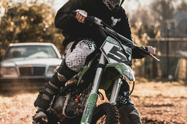 man riding on black and green motocross dirt bike