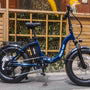 An electric bike is parked on the sidewalk.